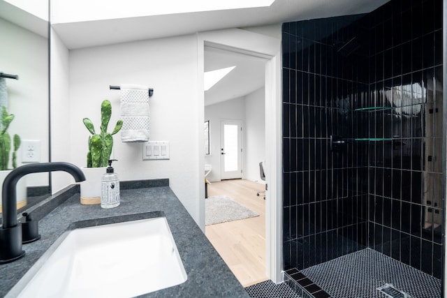 bathroom featuring a tile shower, vanity, and wood-type flooring