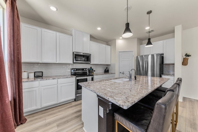 kitchen featuring appliances with stainless steel finishes, white cabinetry, and pendant lighting