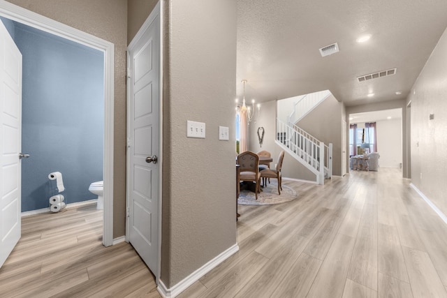 corridor featuring a chandelier and light hardwood / wood-style flooring