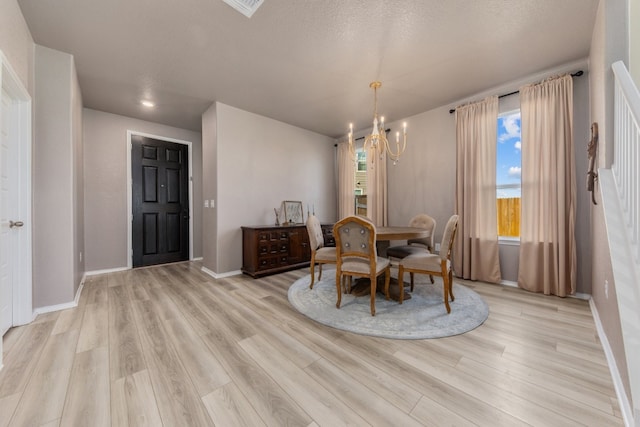 dining space with light hardwood / wood-style flooring, a textured ceiling, and a notable chandelier