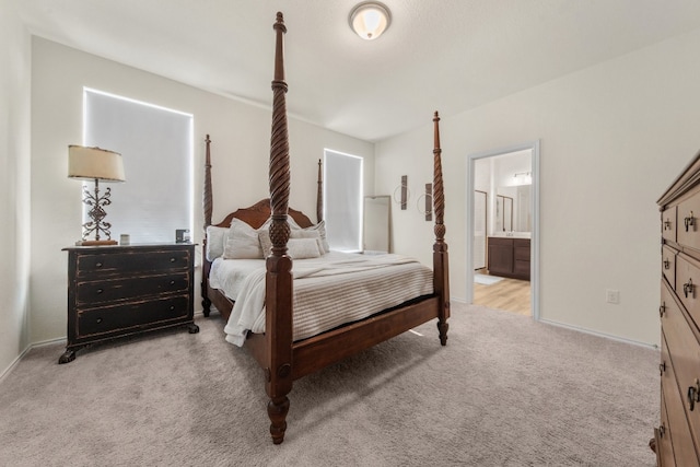 bedroom with light colored carpet and ensuite bathroom