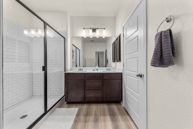 bathroom with hardwood / wood-style flooring, vanity, and walk in shower