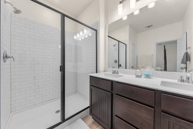 bathroom with hardwood / wood-style floors, vanity, and a shower with shower door