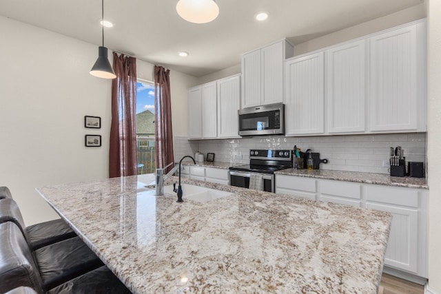 kitchen featuring appliances with stainless steel finishes, backsplash, sink, decorative light fixtures, and white cabinets