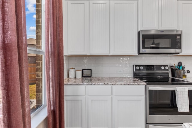 kitchen featuring backsplash, light stone counters, white cabinetry, and stainless steel appliances