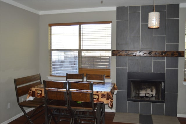 dining room with hardwood / wood-style floors, crown molding, and a tile fireplace