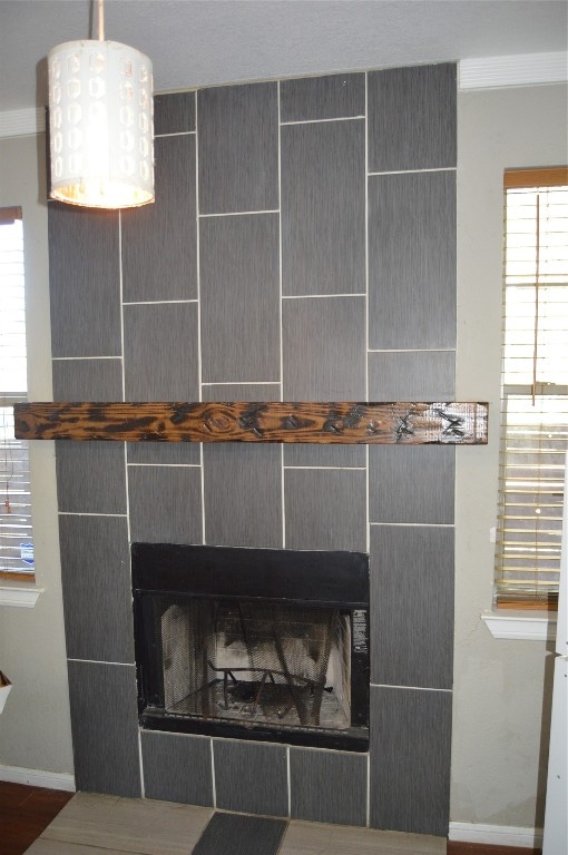 interior details featuring a tiled fireplace and ornamental molding