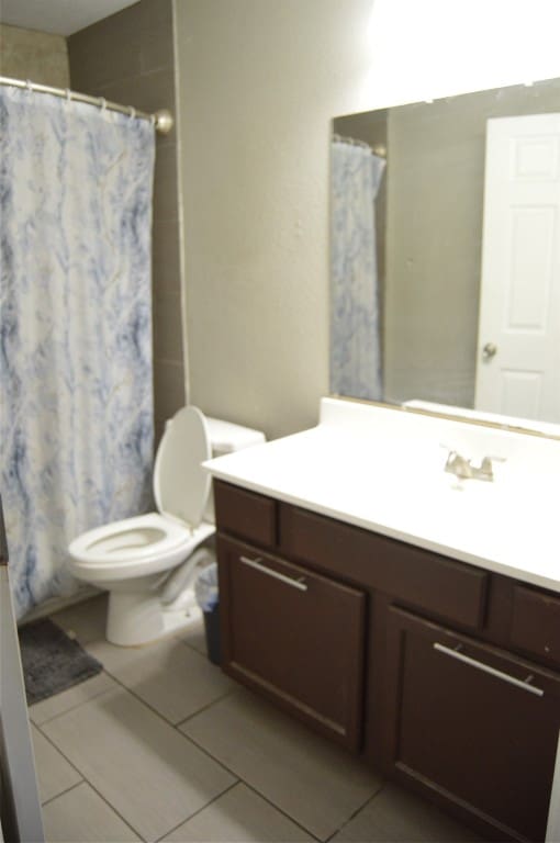 bathroom featuring tile patterned flooring, vanity, toilet, and a shower with shower curtain