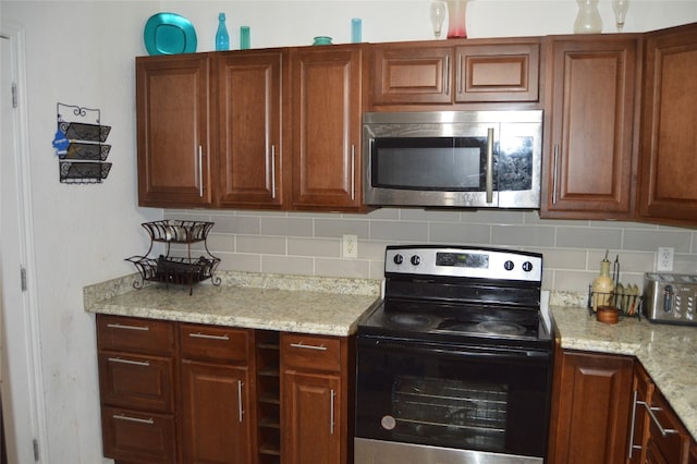 kitchen with backsplash, light stone counters, and appliances with stainless steel finishes