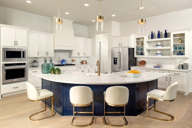 kitchen featuring a kitchen breakfast bar, decorative light fixtures, a large island with sink, and appliances with stainless steel finishes