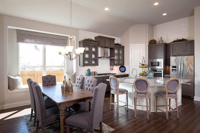 dining room with dark hardwood / wood-style flooring, an inviting chandelier, vaulted ceiling, and sink