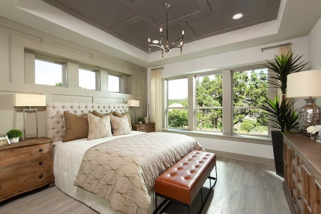 bedroom featuring coffered ceiling, wood-type flooring, a tray ceiling, and a chandelier