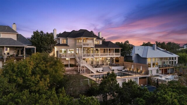 back house at dusk featuring a balcony and a patio