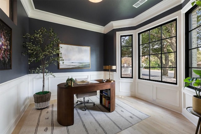 office space with light wood finished floors, visible vents, wainscoting, crown molding, and a decorative wall