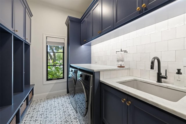 laundry room with cabinet space, washing machine and dryer, baseboards, and a sink