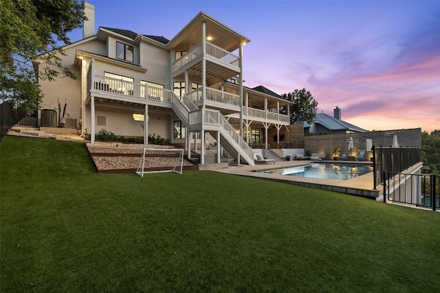 back of property featuring a lawn, stairway, stucco siding, and a balcony