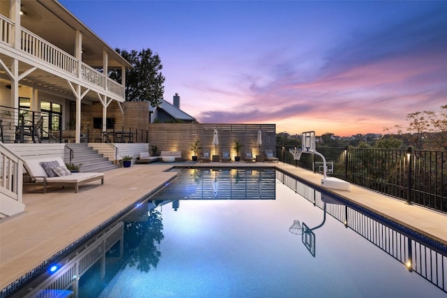 pool at dusk featuring a patio, fence, and a fenced in pool