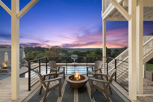 balcony at dusk featuring an outdoor fire pit