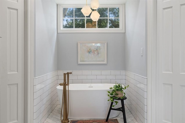 full bath with a wainscoted wall, a soaking tub, and tile walls