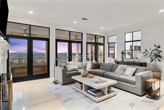 living room with light wood-type flooring, ornamental molding, and french doors