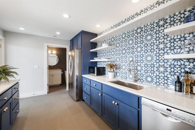 kitchen with appliances with stainless steel finishes, blue cabinets, light countertops, open shelves, and a sink