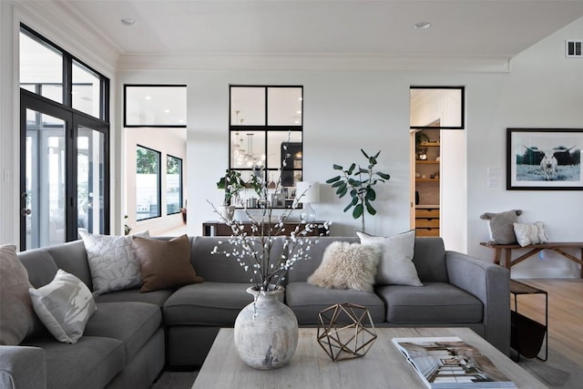 living room featuring wood finished floors, visible vents, and crown molding
