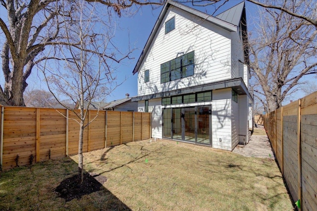 back of house featuring a lawn and a fenced backyard