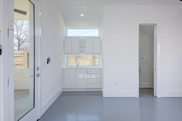 empty room with baseboards, visible vents, concrete flooring, and a wealth of natural light