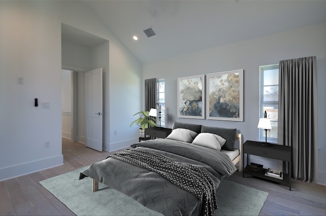 bedroom featuring vaulted ceiling, wood finished floors, visible vents, and baseboards