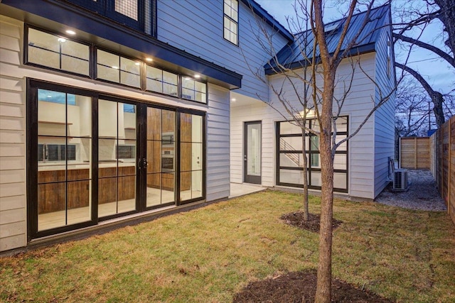 back of property featuring central AC, a lawn, and fence