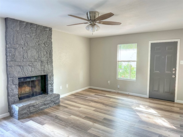 unfurnished living room featuring ceiling fan, light wood-type flooring, and a fireplace