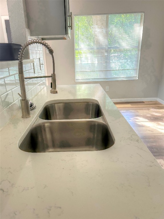 interior details featuring hardwood / wood-style floors, light stone counters, and sink