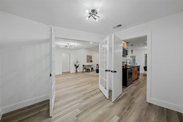 interior space featuring sink, an inviting chandelier, and light wood-type flooring