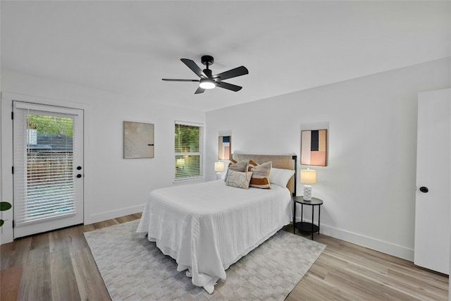 bedroom with access to outside, light hardwood / wood-style flooring, multiple windows, and ceiling fan