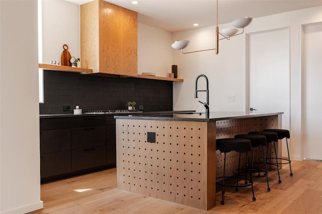2114 Lawnmont Ave, Austin, TX 78756 - bar featuring light wood-style flooring, stovetop, pendant lighting, recessed lighting, and backsplash
