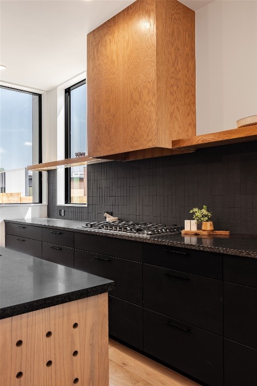 kitchen with backsplash, light hardwood / wood-style floors, and stainless steel gas cooktop