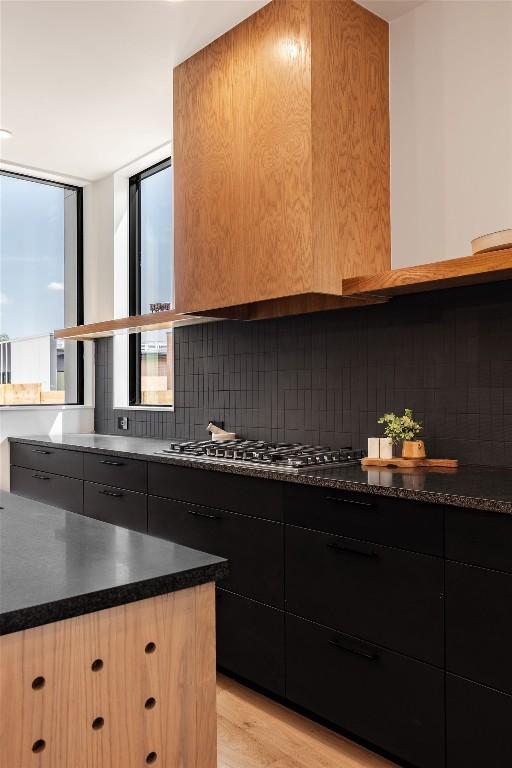 2114 Lawnmont Ave, Austin, TX 78756 - kitchen with backsplash, dark countertops, light wood finished floors, and stainless steel gas cooktop