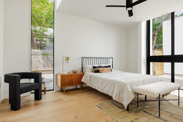 bedroom featuring ceiling fan, light hardwood / wood-style floors, and a wall of windows