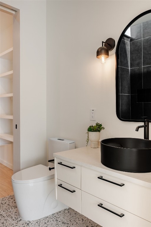 bathroom featuring built in shelves, toilet, vanity, and hardwood / wood-style flooring