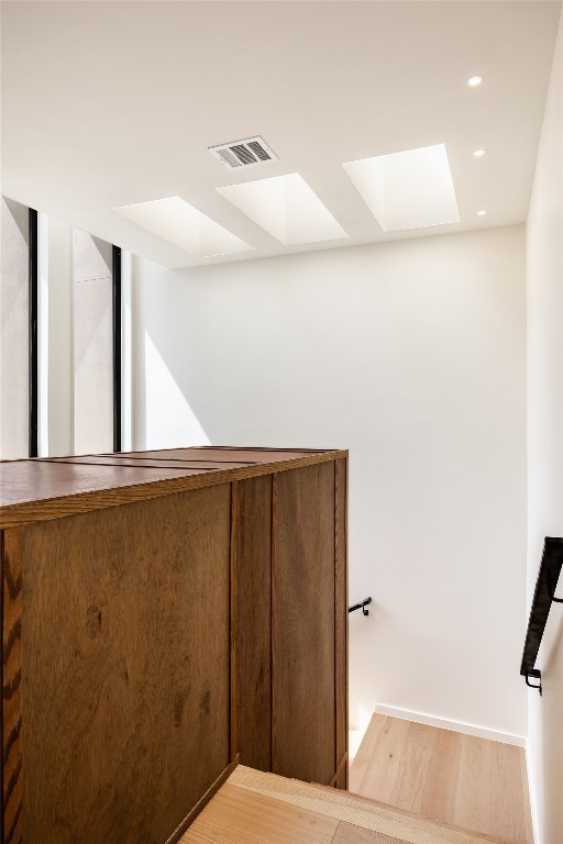 staircase with a skylight and hardwood / wood-style flooring