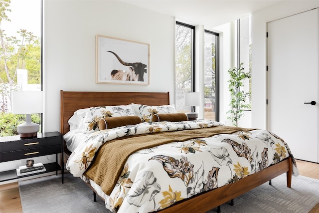 bedroom with floor to ceiling windows and wood-type flooring