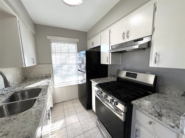 kitchen with white cabinets, sink, gas range, light stone countertops, and light tile patterned floors