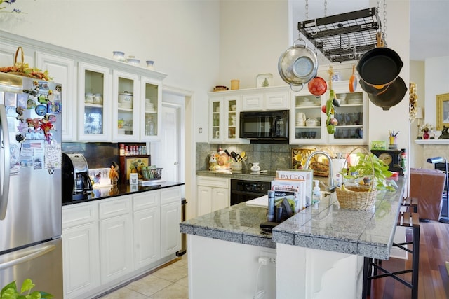 kitchen with black appliances, a kitchen breakfast bar, white cabinets, tasteful backsplash, and light hardwood / wood-style floors