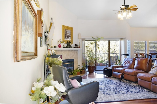 living room with wood-type flooring, ceiling fan, and a tiled fireplace