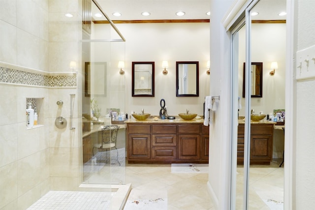 bathroom with vanity, a shower with shower door, and ornamental molding