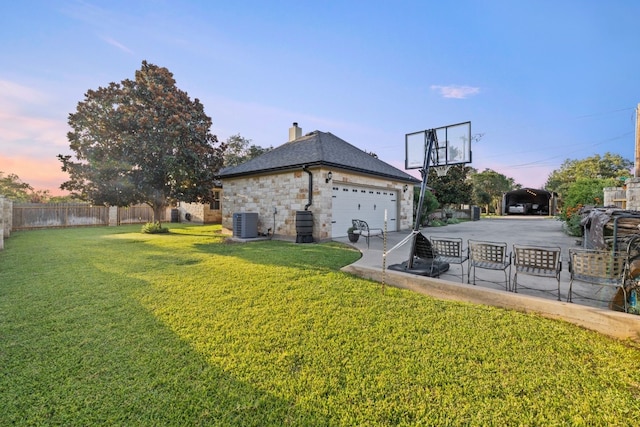 property exterior at dusk with a lawn, central air condition unit, and a garage