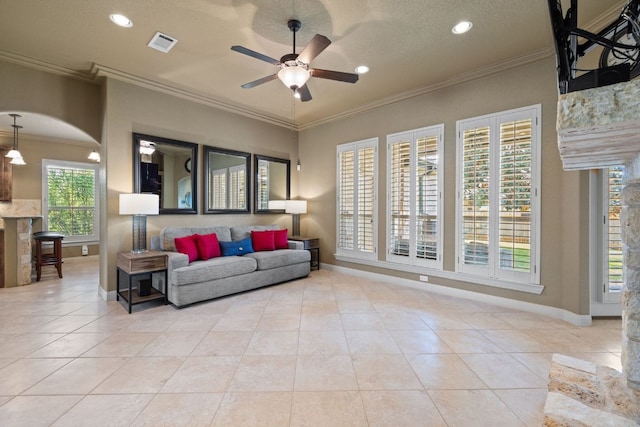 tiled living room with ornamental molding, a textured ceiling, ceiling fan, and a healthy amount of sunlight