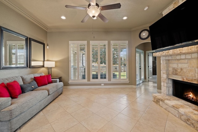 tiled living room featuring ceiling fan, ornamental molding, a fireplace, and a wealth of natural light