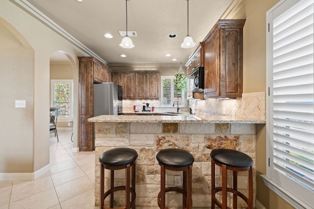 kitchen featuring stainless steel fridge with ice dispenser, kitchen peninsula, ornamental molding, and a wealth of natural light