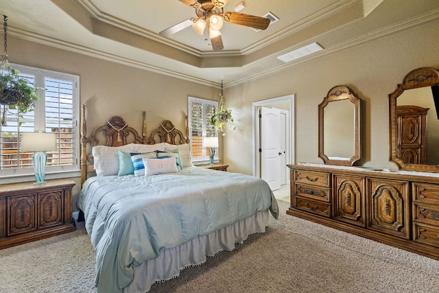 bedroom featuring a tray ceiling, multiple windows, and crown molding